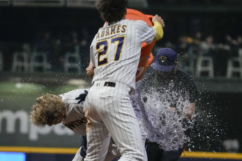 Joey Wiemer, de los Cerveceros de Milwaukee, es empapado por el dominicano Willy Adames, al festejar la victoria sobre los Reales de Kansas City, el sábado 13 de mayo de 2023 (AP Foto/Morry Gash)