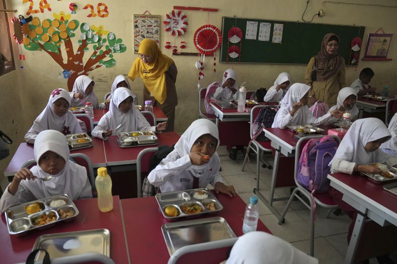 Estudiantes toman sus comidas durante la puesta en marcha del ambicioso programa de comidas gratuitas del presidente Prabowo Subianto para alimentar a los niños y las mujeres embarazadas en todo el país, a pesar de las críticas que dicen que su logística requerida podría dañar las finanzas estatales y la economía de Indonesia, en una escuela primaria en Depok, Java Occidental, Indonesia, lunes, 6 de enero de 2025. (AP foto/Dita Alangkara)