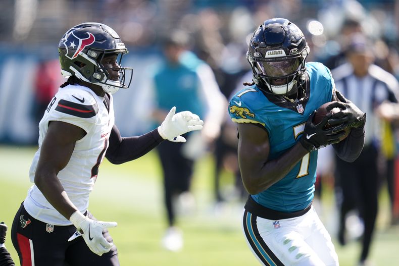 El receptor de los Jaguars de Jacksonville Brian Thomas Jr. sostiene el balón frente al cornerback de los Texans de Houston Kamari Lassiter en el encuentro de la NFL del domingo 21 de septiembre del 2025. (AP Foto/John Raoux)