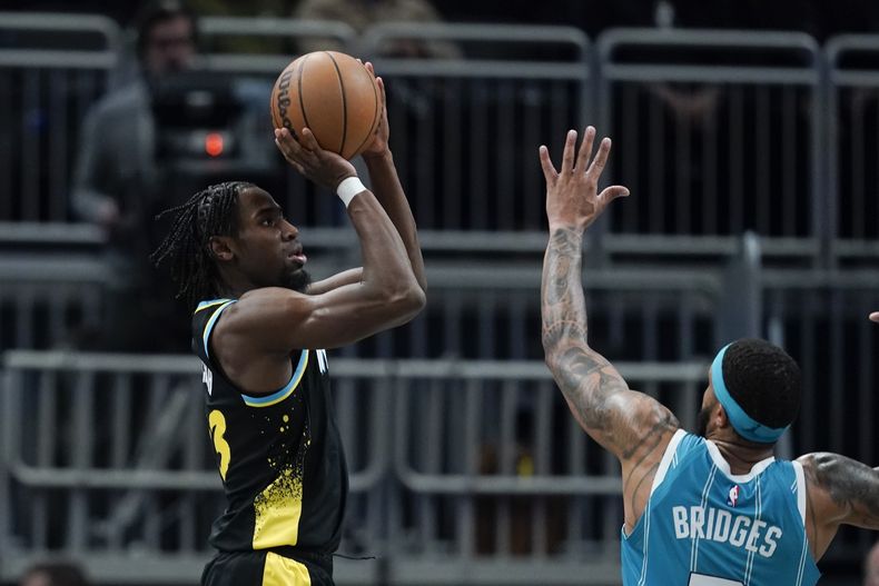 Aaron Nesmith (23) dispara por los Pacers de Indiana frente a Miles Bridges, de los Hornets de Charlotte, durante el duelo del miércoles 20 de diciembre de 2023 (AP Foto/Darron Cummings)