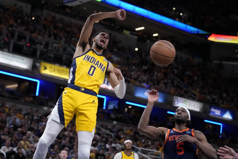 Tyrese Haliburton (0), de los Pacers de Indiana, retaca el balón ante la mirada de Precious Achiuwa (5), de los Knicks de Nueva York, durante la segunda mitad del juego de segunda ronda de los playoffs de la NBA, el domingo 12 de mayo de 2024, en Indianápolis. (AP Foto/Michael Conroy)