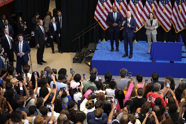 El presidente Joe Biden, en el centro del escenario, habla mientras el gobernador de Maryland, Wes Moore, a la izquierda, y la candidata presidencial demócrata a la vicepresidenta, Kamala Harris, a la derecha, escuchan en un evento para anunciar los esfuerzos de la administración para reducir los costos de algunos medicamentos recetados, en Prince Georges Community College en Largo, Maryland, el jueves 15 de agosto de 2024. (Foto AP/Susan Walsh)