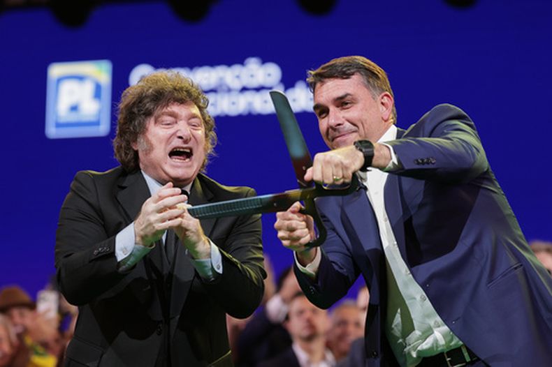 El senador brasileño Flavio Bolsonaro, a la derecha, sostiene unas tijeras gigantes, acompañado por el presidente argentino Javier Milei, durante la convención del Partido Liberal en la que Bolsonaro fue confirmado como candidato presidencial del partido, en São Paulo, el sábado 25 de julio de 2026. (Foto AP/Ettore Chiereguini)
