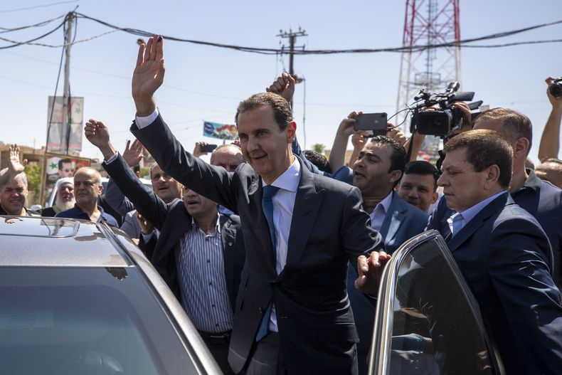 ARCHIVO - El presidente sirio Bashar Assad saluda a sus partidarios en una casilla electoral en Douma, cerca de Damasco, Siria, 26 de mayo de 2021. La justicia francesa emitió órdenes de arresto por crímenes de guerra para Assad, su hermano Maher y dos generales sirios el miércoles 15 de noviembre de 2023. (AP Foto/Hassan Ammar, File)