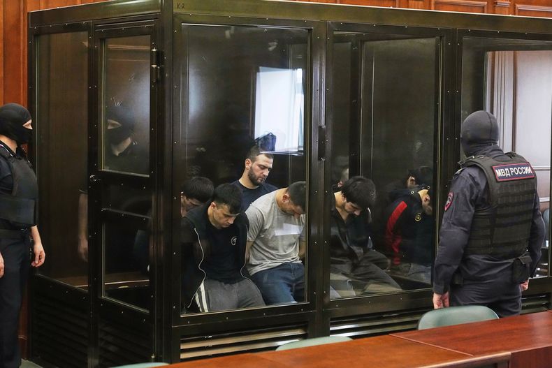 Sospechosos acusados de participar en un ataque terrorista en el recinto de conciertos Crocus City Hall el 22 de marzo de 2024, sentados en una jaula de vidrio antes de una audiencia en el Tribunal Militar del 2º Distrito Occidental en Moscú, Rusia, el lunes 4 de agosto de 2025. (AP Foto/Pavel Bednyakov)