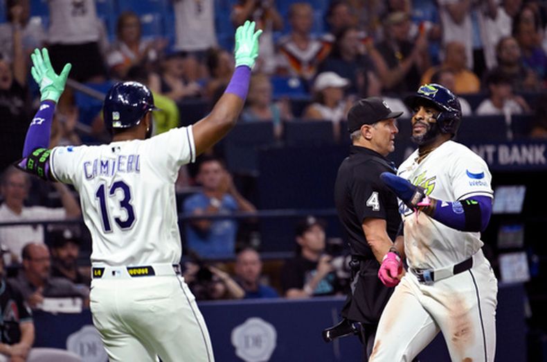 Junior Caminero (13) y Yandy Díaz, de los Rays de Tampa Bay, celebran después de que Díaz anotara gracias a un doble de Jonathan Aranda (no aparece en la foto) durante la séptima entrada de un partido de béisbol contra los Diamondbacks de Arizona, el viernes 26 de junio de 2026, en St. Petersburg, Florida. (Foto AP/Jason Behnken)
