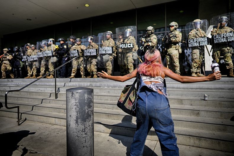 Una manifestante desafía a una línea de guardias nacionales de California que protege un edificio federal en el centro de Los Ángeles en el lunes 9 de junio de 2025. (AP Foto/Eric Thayer)