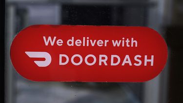 Un letrero del servicio de entrega de comidas DoorDash en la puerta de una franquicia de Dunkin Donuts, el 27 de febrero de 2023, en Methuen, Massachusetts. (AP Foto/Charles Krupa, Archivo)