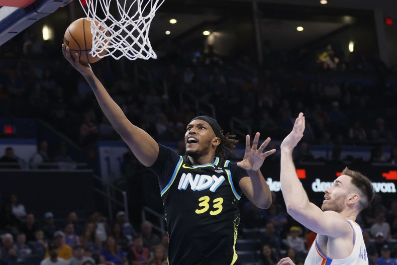El pívot de los Pacers de Indiana Myles Turner salta para tirar de bandeja el balón frente al alero del Thunder de Oklahoma City Gordon Hayward en el encuentro de la NBA del martes 12 de marzo del 2024. (AP Foto/Nate Billings)