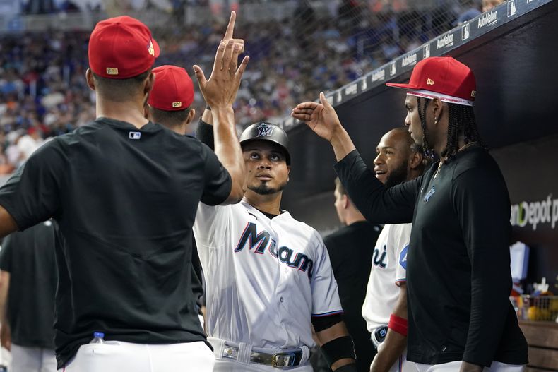Luis Arráez (centro) de los Marlins de Miami es felicitado tras anotar mediante un jonrón de Jesús Sánchez en el juego ante los Cardenales de San Luis, el martes 4 de julio de 2023, en Miami. (AP Foto/Lynne Sladky)