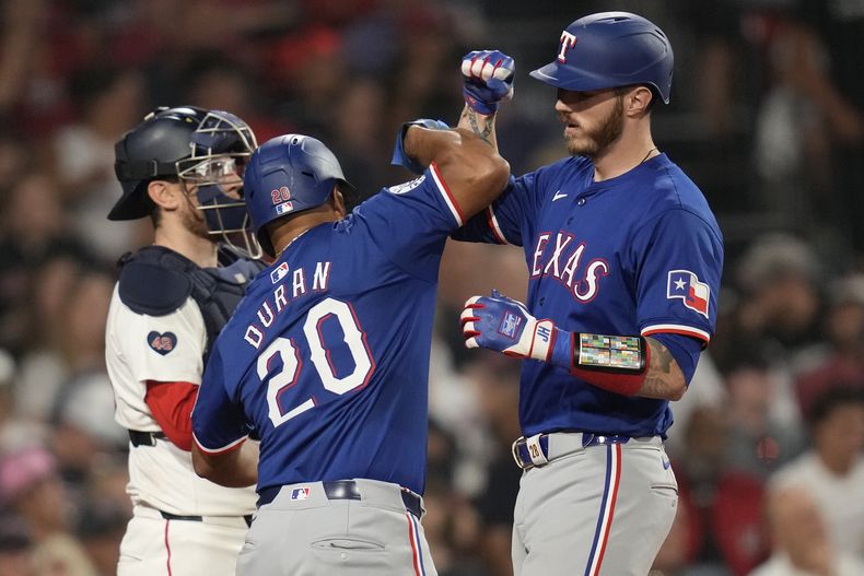 El dominicano Ezequiel Durán, de los Rangers de Texas, felicita a su compañero Jonah Heim, quien conectó un jonrón de dos carreras en el décimo inning del encuentro ante los Medias Rojas de Boston, el miércoles 14 de agosto de 2024 (AP Foto/Charles Krupa)
