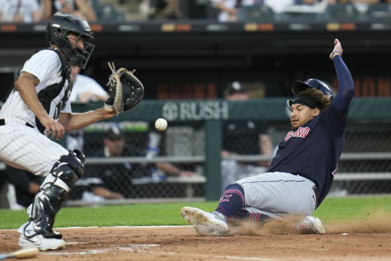 Josh Naylor, de los Guardianes de Cleveland, se desliza para anotar frente al cátcher mexicano Seby Zavala, de los Medias Blancas de Chicago, el jueves 27 de julio de 2023 (AP Foto/Erin Hooley)