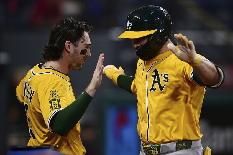 Shea Langeliers de los Atléticos, derecha, es felicitado por Jacob Wilson después de batear un jonrón de dos carreras ante el lanzador relevista de los Guardianes de Cleveland, Nic Enright, durante la octava entrada de un partido de béisbol, el sábado 19 de julio de 2025, en Cleveland. (AP Photo/David Dermer)