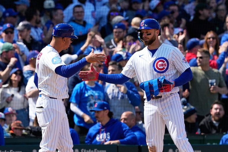 Michael Busch, de los Cachorros de Chicago (derecha), celebra con el coach de tercera base Quintin Berry (izquierda) tras conectar un triple de tres carreras durante la quinta entrada de un partido de béisbol contra los Diamondbacks de Arizona, el domingo 3 de mayo de 2026, en Chicago. (AP Foto/Nam Y. Huh)