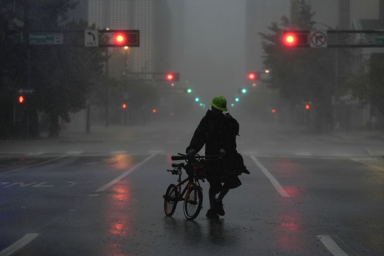 Ron Rook, que dijo que buscaba gente pudiese necesitar su ayuda o escombros que retirar, camina bajo la lluvia y el viento en el desierto centro de Tampa, antes de la llegada del huracán Milton a Florida, el 9 de octubre de 2024. (AP Foto/Rebecca Blackwell)