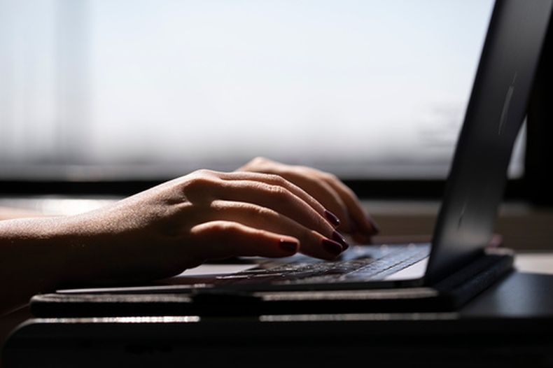 Una mujer trabaja en una laptop en un tren en Nueva Jersey, el 18 de mayo del 2021. (AP foto/Jenny Kane)