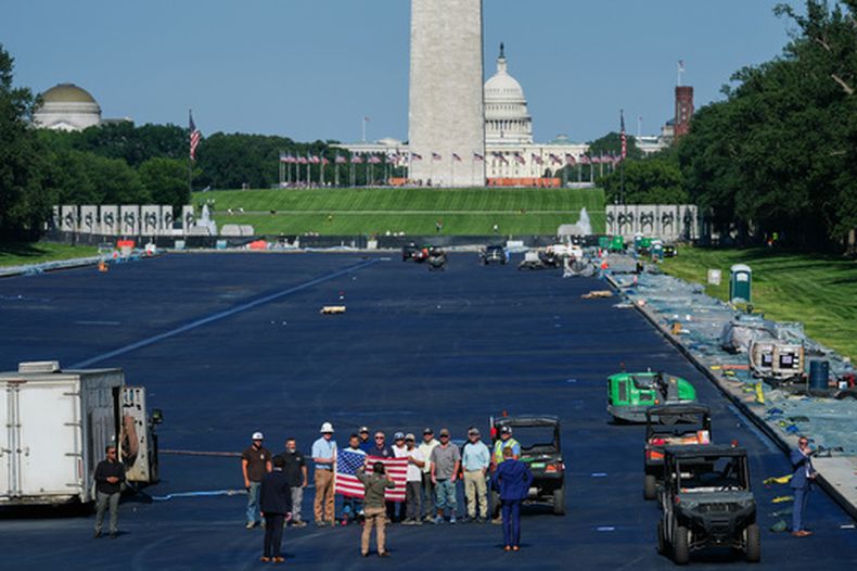 El secretario del Interior, Doug Burgum, al centro, posa para una fotografía con trabajadores mientras recorre el Estanque Reflectante del Monumento a Lincoln después de que se le colocó una cubierta antes de los festejos por el aniversario 250 de la independencia de Estados Unidos, el miércoles 3 de junio de 2026, en Washington. (AP Foto/Julia Demaree Nikhinson)