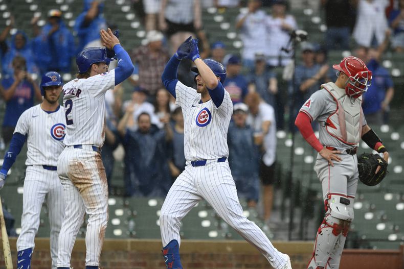 Michael Busch, centro, de los Cachorros de Chicago, celebra con su compañero de equipo Nico Hoerner después de anotar con jonrón de dos carreras mientas el receptor de los Angelinos de Los Ángeles Logan OHoppe, derecha, observa durante la séptima entrada del juego de beisbol del domingo 7 dejulio de 2024, en Chicago. (AP Foto/Paul Beaty)