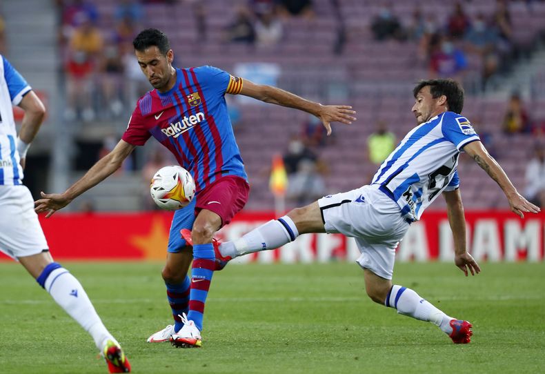ARCHIVO - David Silva (derecha) de la Real Sociedad pugna por el balón con Sergio Busquets del Barcelona en un partido de la Liga de España, el domingo 15 de agosto de 2021. (AP Foto/Joan Monfort)
