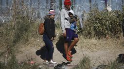 Migrantes con un bebé caminan hacia el lado estadounidense de la frontera desde Ciudad Juárez, México, el 27 de diciembre de 2023. (AP Foto/Christian Chávez)