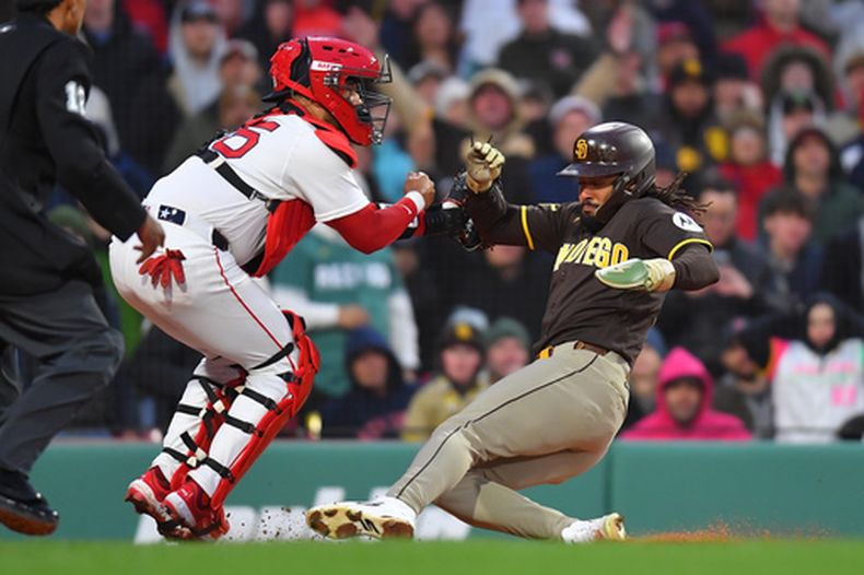 El dominicano Fernando Tatis Jr., de los Padres de San Diego, se desliza para anotar frente al venezolano Carlos Narváez, de los Medias Rojas de Boston, el sábado 4 de abril de 2026 (AP Foto/Steven Senne)