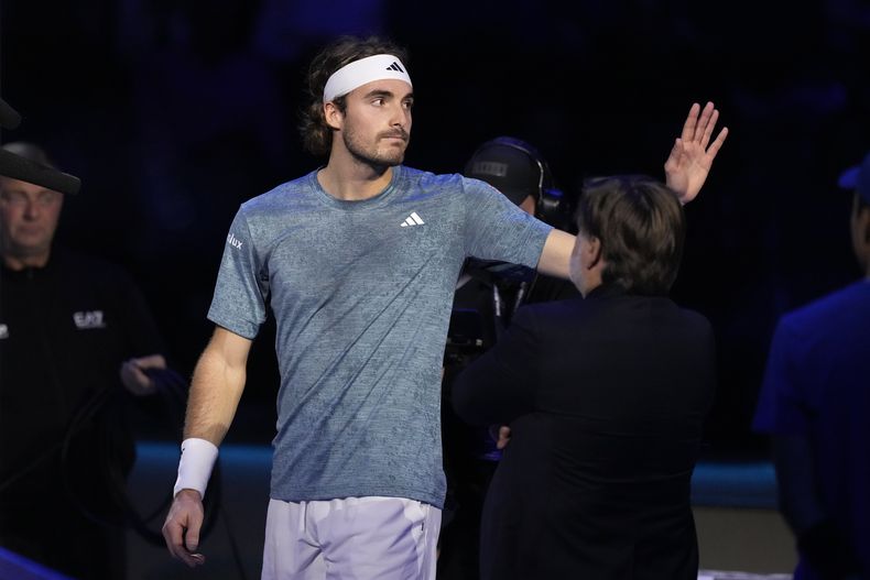 El griego Stefanos Tsitsipas saluda a sus seguidores mientras deja la cancha tras darse de baja del duelo ante el danés Holger Rune por una lesión en las Finales de la ATP en Turín, Italia el martes 14 de noviembre del 2023. (AP Foto/Antonio Calanni)