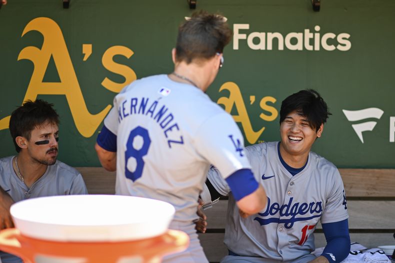 El puertorriqueño de los Dodgers de Los Ángeles, Enrique Hernández (8) y Shohei Ohtani conversan en el banco previo al juego de béisbol ante los Atléticos de Oakland, el domingo 4 de agosto de 2024, en Oakland, California. (AP Foto/Eakin Howard)