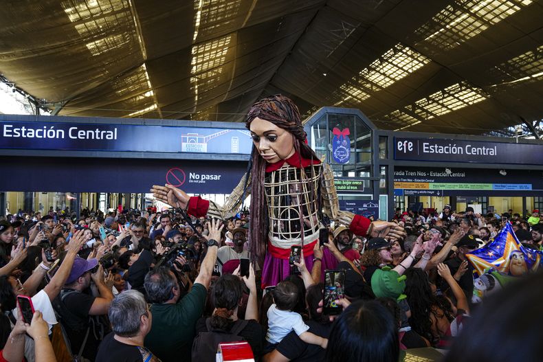 La Pequeña Amal, una marioneta que representa a una niña refugiada siria de 10 años, saluda a los niños durante la inauguración del Festival Teatro a Mil en la Estación Central de Trenes de Santiago, Chile, el viernes 3 de enero de 2025. (AP Foto/Esteban Felix)
