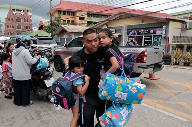 Un hombre lleva dos niñas escolares ante una escuela donde hubo un tiroteo en la provincia tailandesa de Nonthaburi, el viernes 7 de agosto de 2026. (AP Foto/Wason Wanichakorn)