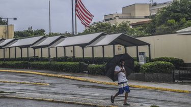 Un hombre camina frente a la embajada de EEUU en Kingston, Jamaica, mientras caen lluvias provocadas por la tormenta tropical Rafael el martes 5 de noviembre de 2024. Rafael se fortaleció el miércoles 6 de noviembre y se convirtió en un ciclón categoría 3 el miércoles 6 de noviembre, en las inmediaciones de las costas sur occidental de Cuba, (AP Foto/Collin Reid)