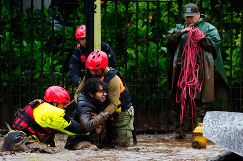 Un hombre es rescatado por socorristas después de que las fuertes lluvias provocaran un aluvión en el distrito de Las Condes, en Santiago de Chile, el jueves 8 de octubre de 2026. (AP Foto/Esteban Félix)