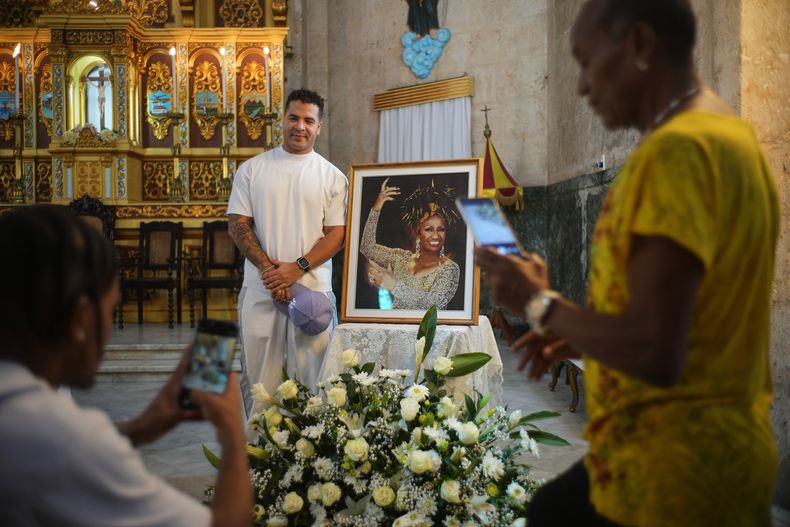 El reguetonero cubano Yomil posa junto a una imagen enmarcada de la fallecida cantante Celia Cruz tras asistir a una misa conmemorativa por el centenario de su nacimiento en la iglesia Virgen del Cobre o Nuestra Señora de la Caridad en La Habana, el martes 21 de octubre de 2025. (Foto AP/Ramon Espinosa)
