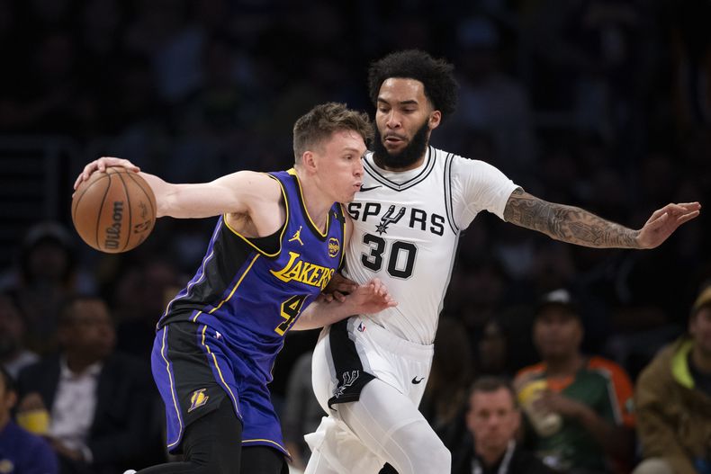 El base de los Lakers de Los Ángeles Dalton Knecht avanza hacia la canasta frente al alero de los Spurs de San Antonio Julian Champagnie en el encuentro del lunes 17 de marzo del 2025. (AP Foto/Kyusung Gong)