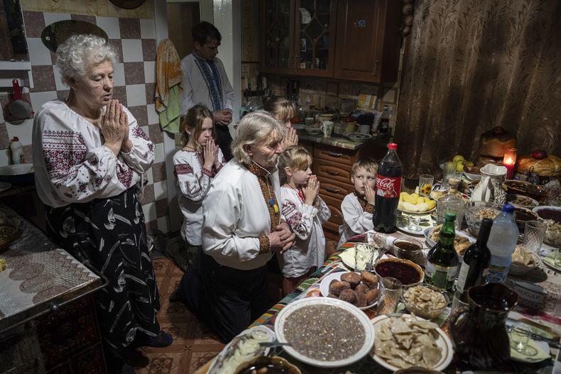 La familia Zelenchuk reza antes de su cena de Navidad en la localidad de Kryvorivnia, Ucrania, el domingo 24 de diciembre de 2023. (AP Foto/Evgeniy Maloletka)