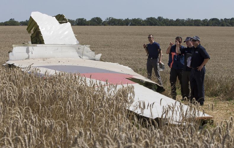 ARCHIVO - Investigadores australianos y holandeses examinan una pieza del avión de Malaysia Airlines derribado cerca de la localidad de Hrabove, en una zona de la provincia oriental ucraniana de Donetsk, controlada por prorrusos, el 1 de agosto de 2014. (AP Foto, archivo)