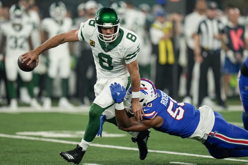 Aaron Rodgers (8), quarterback de los Jets de Nueva York, es derribado por atendido por Greg Rousseau (50) de los Bills de Buffalo, el lunes 11 de septiembre de 2023, en East Rutherford, Nueva Jersey. (AP Foto/Seth Wenig)