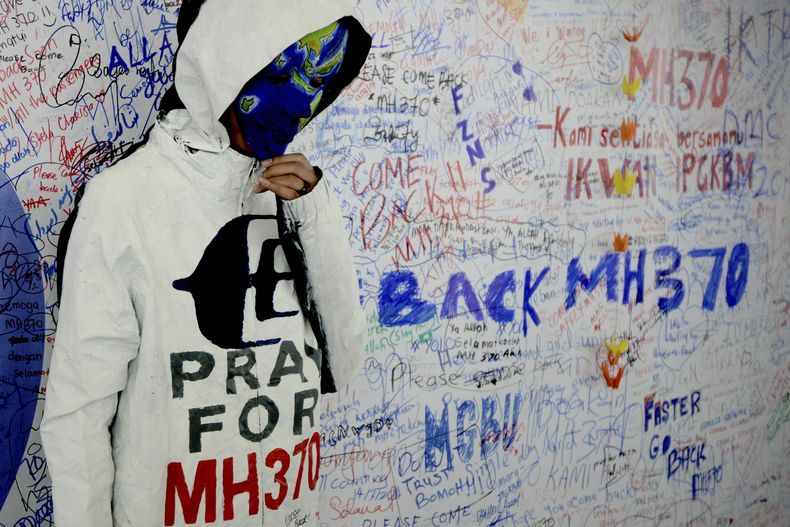 Una mujer no identificada con la cara pintada con motivos alusivos a la desaparici&oacute;n del vuelo MH370 de Malaysia Airline posa frente al "muro de la esperanza" en el aeropuerto de Kuala Lumpur en Sepang, Malasia, el lunes 17 de marzo de 20