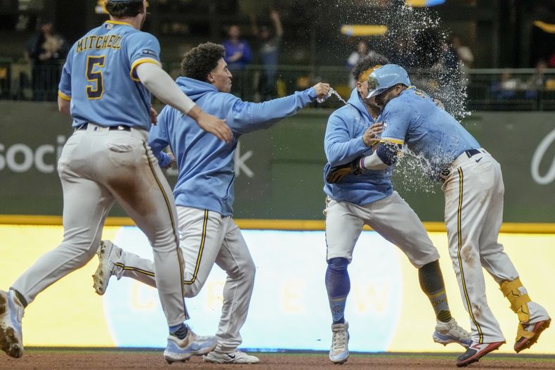 Carlos Santana, de los Cerveceros de Milwaukee, celebra con sus compañeros de equipo después de que con su imparable durante la 10ma entrada dejaran tendidos a los Cachorros de Chicago, el viernes 29 de septiembre de 2023, en Milwaukee. Los Cerveceros ganaron 4-3. (AP Foto/Morry Gash)