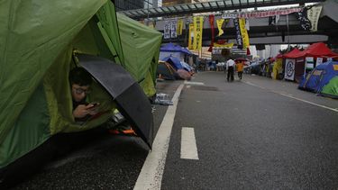 americateve | Un manifestante pro democracia consulta su tel&eacute;fono movil en una tienda de campa&ntilde;a en una zona ocupada fuera de la sede del gobierno en el distrito de Admiralty, en Hong Kong,el 8 de noviembre de 2014. (Foto AP/Vincent Yu)