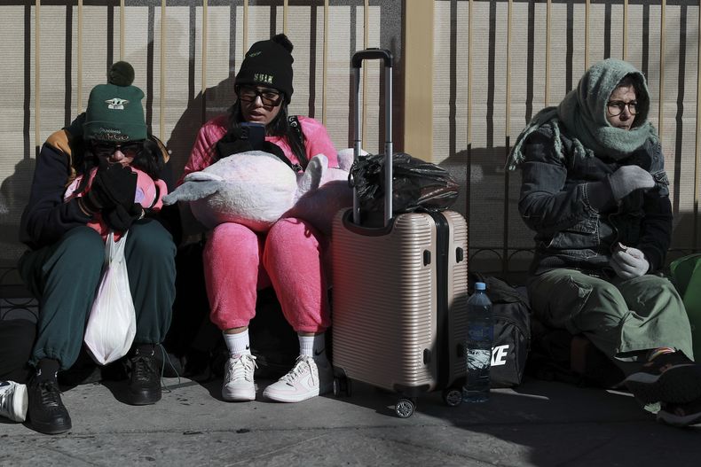Migrantes con cita previa esperan para presentar sus documentos a agentes de inmigración estadounidenses como parte de sus solicitudes de asilo, en el puente internacional Paso del Norte en Ciudad Juárez, México, en la frontera con El Paso, Texas, el lunes 20 de enero de 2025, día de la toma de posesión del presidente estadounidense Donald Trump. (AP Foto/Christian Chavez)