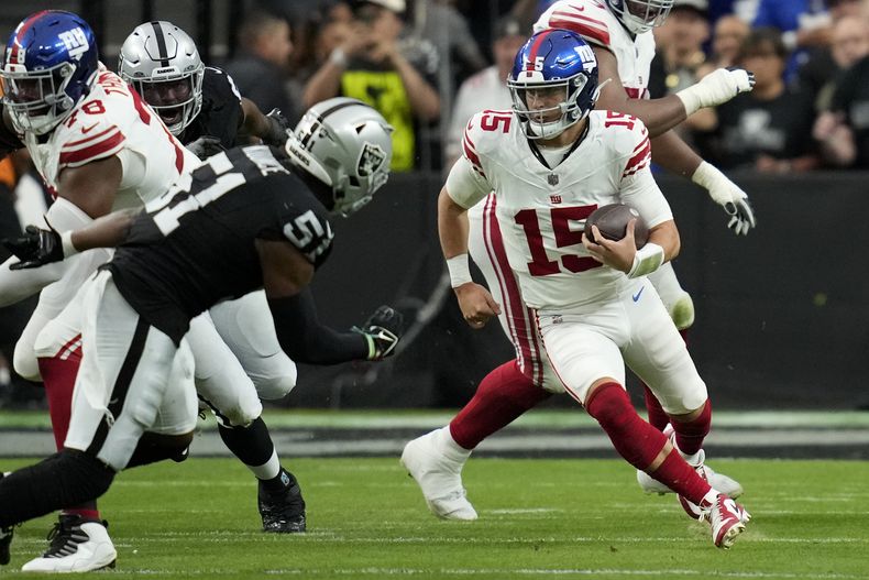 Tommy DeVito (15), quarterback de los Giants de Nueva York, se mueve para eludir a defensivos de los Raiders de Las Vegas durante la primera mitad del juego de la NFL, el domingo 5 de noviembre de 2023, en Las Vegas. (AP Foto/John Locher)