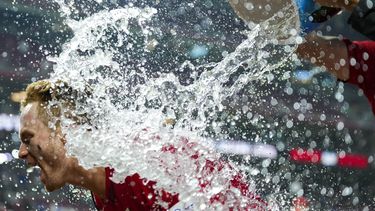 Matt McLain es empapado por sus compañeros, luego de empujar la carrera de la victoria de los Rojos de Cincinnati sobre los Dodgers de Los Ángeles, el martes 6 de junio de 2023 (AP Foto/Aaron Doster)