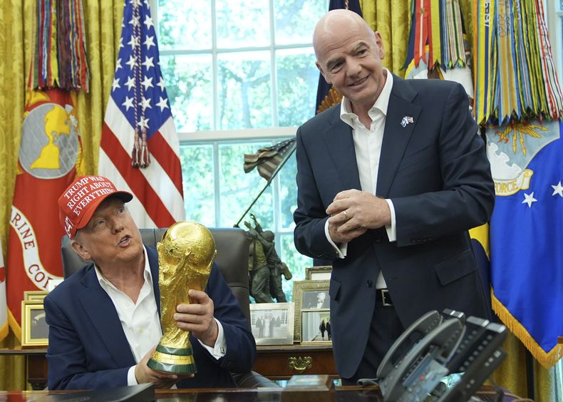 El presidente de los Estados Unidos Donald Trump sostiene el trofeo del campeón de la Copa Mundial de la FIFA en la Oficina Oval junto al presidente de la FIFA Gianni Infantino el viernes 22 de agosto del 2025. (AP Foto/Jacquelyn Martin)