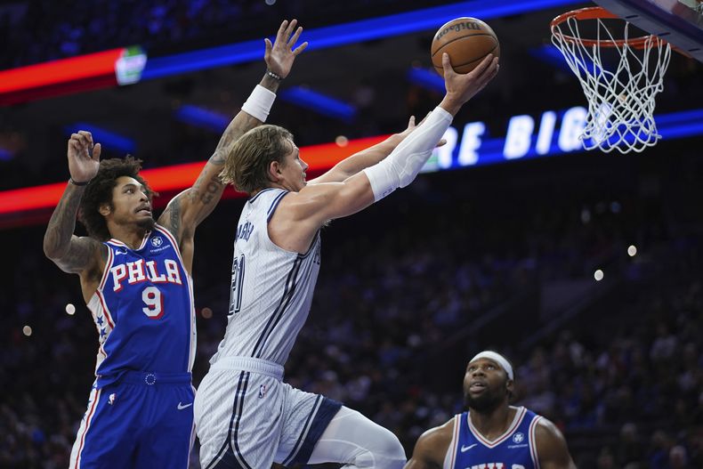 Moritz Wagner, centro, del Magic de Orlando, se alista a encestar entre Kelly Oubre Jr., izquierda, y Guerschon Yabusele, de los 76ers de Filadelfia, durante la primera mitad del juego de baloncesto de la NBA, el miércoles 4 de diciembre de 2024, en Filadelfia. (AP Foto/Matt Slocum)