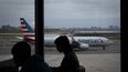 Gente esperando a vuelos mientras un avión de American Airlines circula por la pista en el aeropuerto LaGuardia (LGA) en el barrio de Queens, Nueva York, el domingo 9 de noviembre de 2025. (AP Foto/Adam Gray)