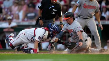 Adley Rutschman, derecha, de los Orioles de Baltimore, es puesto out por el receptor de los Rojos de Cincinnati, Jose Trevino, izquierda, durante la tercera entrada del juego de béisbol de Grandes Ligas, el sábado 4 de julio de 2026, en Cincinnati. (AP Foto/Carolyn Kaster)