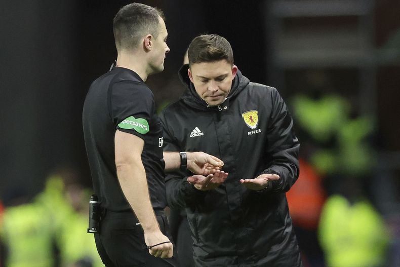 El árbitro Don Robertson entrega un objeto que le lanzaron desde las gradas al jugador Arne Engels del Celtic durante el encuentro ante Rangers en la Premiership de Escocia el jueves 2 de enero del 2025. (Steve Welsh/PA via AP)