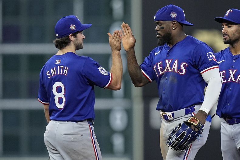 El tercera base de los Rangers de Texas John Smith (8) y el jardinero derecho cubano Adolis García celebran luego del juego de béisbol ante los Astros de Houston, el viernes 12 de abril de 2024, en Houston. (AP Foto/Kevin M. Cox)