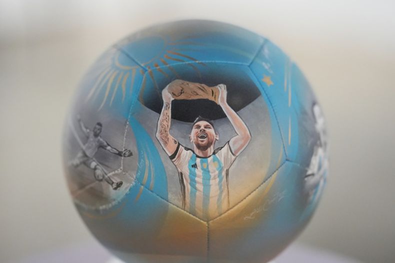 La imagen de Lionel Messi alzando el trofeo del Mundial en un balón pintado a mano por la artista Lili Cantero, el jueves 4 de junio de 2026, en Miami. (AP Foto/Rebecca Blackwell)