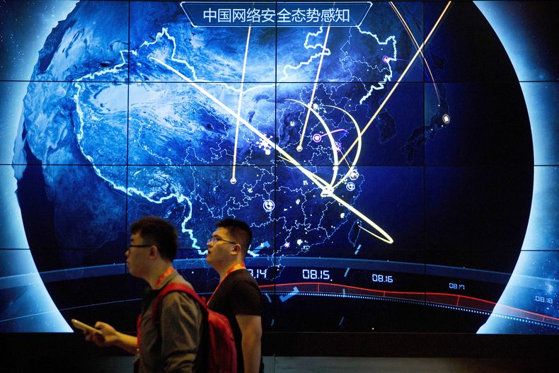 ARCHIVO - Asistentes pasan por delante de una pantalla que muestra ciberataques recientes en China, en la Conferencia de Seguridad en Internet, en Beijing, el 12 de septiembre de 2017. (AP Foto/Mark Schiefelbein, archivo)
